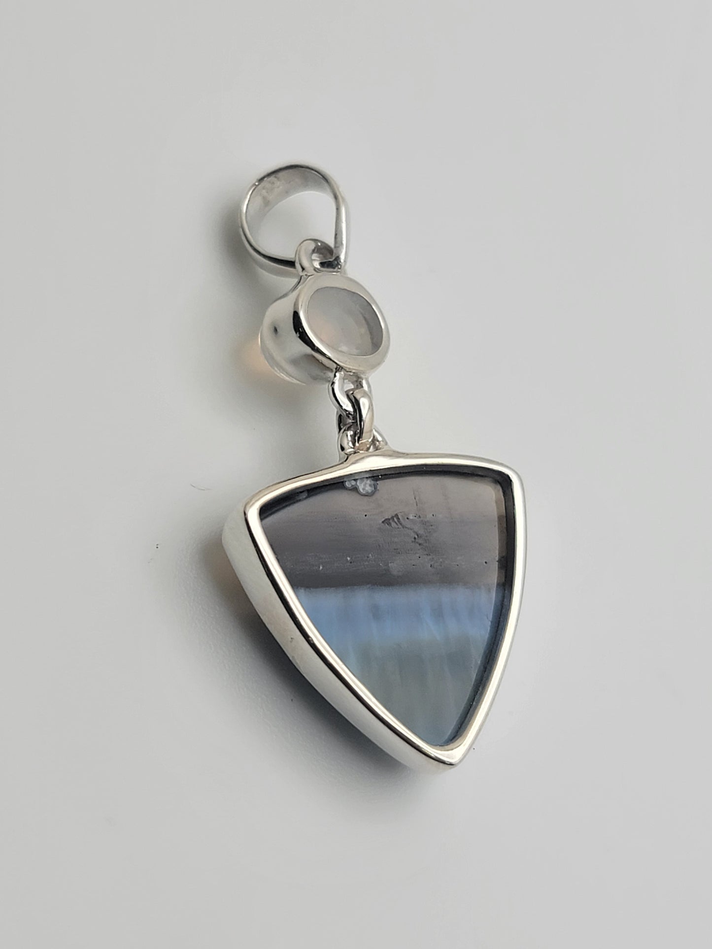 Stunning Blue Opal and Moonstone 925 Sterling Silver Pendant showcasing the unique beauty of a blue opal triangle with a moonstone accent. This handmade artisan jewelry piece is a great choice for anyone seeking blue opal pendants or ocean-inspired jewelry. An ideal gift jewelry piece, it's perfect for casual wear and an excellent addition to birthstone jewelry collections.